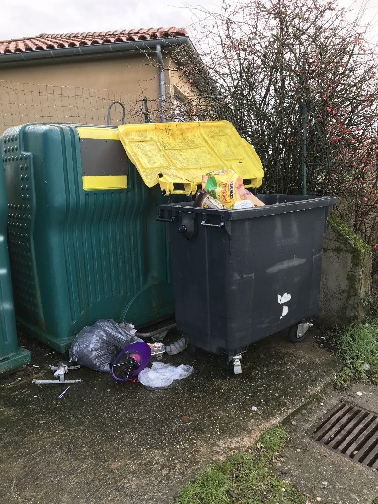 Le bac à couvercle jeune est ouvert, le sac de déchets est posé au sol. Bac jaune ouvert et sac de déchets posé au sol.